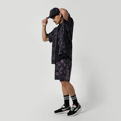 Man wearing black patterned surf shirt, shorts, and cap, styled for watersports in Whitstable.